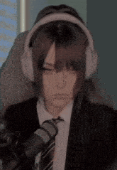 a girl in a suit and tie is wearing headphones and a microphone .