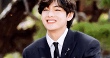 a young man in a suit and tie is smiling and looking at the camera .