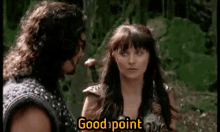 a man and a woman are standing next to each other in the woods and the woman is talking to the man .