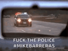 a police car is driving down the road in the rear view mirror .