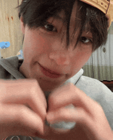 a person wearing a crown is making a heart with their hands