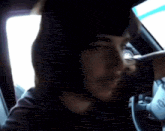 a man with a beard is sitting in a car with his hand on the steering wheel