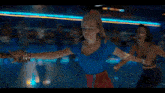 a woman in a blue shirt and red skirt is rollerblading with other people