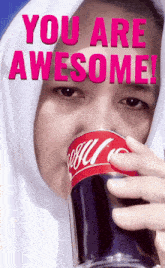 a woman drinking a can of coca cola with the words " you are awesome " behind her