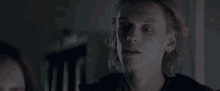 a young man with long blonde hair is looking at something in the dark