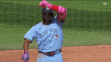a baseball player for the blue jays is wearing pink gloves and a helmet