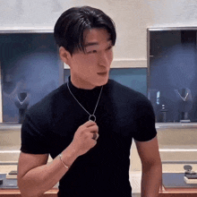 a man wearing a black shirt and a necklace is standing in a store .