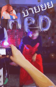 a person taking a picture of a woman in a red dress in front of balloons that say gd