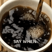 a cup of coffee is being poured into a bowl with the words `` say when '' written on the bottom .