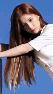 a woman with very long hair is wearing a white shirt against a blue sky .