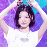 a woman with short hair is wearing a white shirt with a heart on it and a microphone .