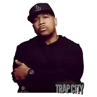 a man wearing a la hat is standing in front of a trap city poster