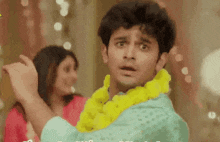 a man is wearing a yellow lei around his neck and a woman is standing behind him .