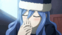 a girl with blue hair is wearing a santa hat and covering her mouth with her hands