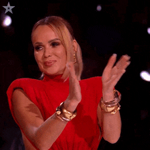 a woman in a red dress is clapping her hands in front of a star