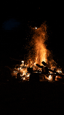 a large fire is burning in the dark and sparks are flying in the air