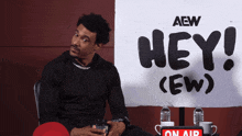 a man is sitting in front of a sign that says hey