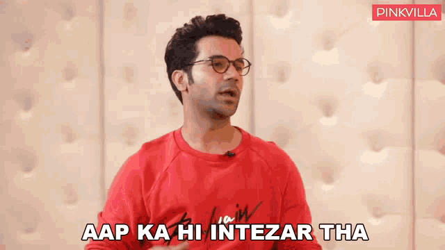 a man wearing glasses and a red sweater says 