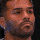 a close up of a man 's face with a beard and earring