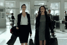 two women walking in a hallway with a sign that says dilsh