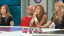 a group of girls sitting at a table with a sign that says " 대단하다 " on it