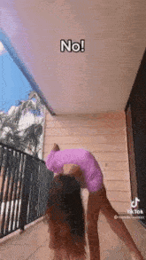 a woman is doing a yoga pose on a balcony while wearing a purple shirt .
