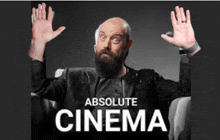 a bald man with a beard is sitting in a chair with his hands in the air and the words absolute cinema above him