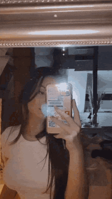 a woman taking a picture of herself in a mirror with her phone