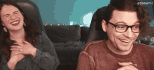 a man and a woman are laughing in front of a screen that says azaaami on it