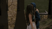 a man in a blue hoodie is hugging a woman