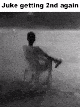 a black and white photo of a man sitting on a chair in the water with the caption juke getting 2nd again