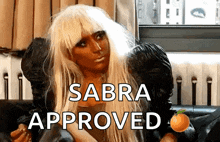 a woman sitting on a couch with the words sabra approved written above her