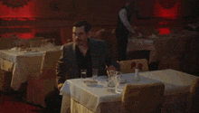 a man sits at a table in a restaurant with a white table cloth