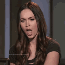 a woman with long hair is sticking her tongue out while wearing a black shirt .
