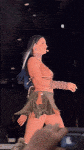 a woman with blue hair is walking on stage