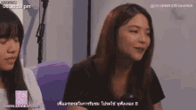 two women are sitting next to each other on a couch and talking .