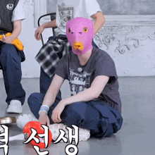 a man wearing a purple mask sits on the floor