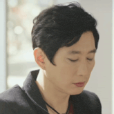 a close up of a person 's face with their eyes closed and a necklace around their neck