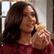 a woman in a red top is holding a cupcake in her hand