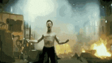 a man without a shirt is dancing in front of a fire