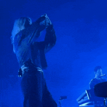 a woman in a black jacket is dancing in the dark