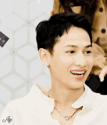 a young man wearing a necklace and a white shirt with the letter ap on the sleeve