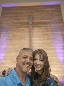 a man and a girl are posing for a picture in front of a wooden cross