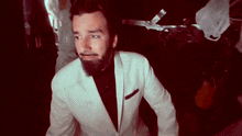 a man with a beard in a white suit