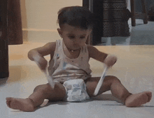 a little boy is sitting on the floor with a diaper on