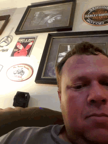 a harley davidson sign hangs on a wall next to a man