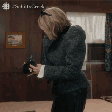 a woman from schitts creek is holding a wallet