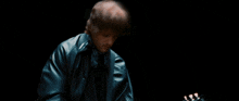a man in a black jacket playing a guitar