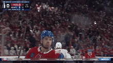 a hockey player in a red white and blue jersey stands on the ice with his arms in the air