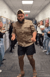 a group of people are dancing in a hallway with an exit sign on the wall